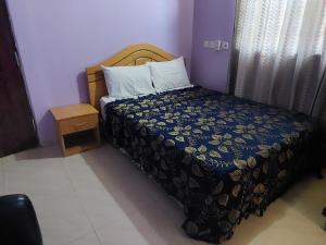 a bedroom with a bed with a blue comforter at NABTEL HOTEL in Spintex