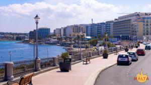 a city street with cars parked on a sidewalk next to the water at B8 Luxury Suites - brand NEW - just 2 mins from the beach in St. Paul's Bay