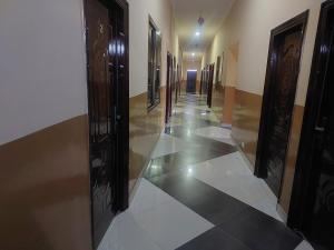 a hallway with black doors and white tile floors at NABTEL HOTEL in Spintex