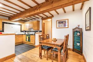 a kitchen with a wooden table and a wooden ceiling at Threshers Barn and Shire Horse Barn in Cawston