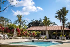 a swimming pool in front of a house with palm trees at Miradas Arenal Hotel & Hotsprings in Fortuna