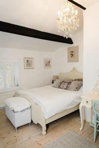 a white bedroom with a bed and a chandelier at 1800 Period Grade 2 Listed Cottage Addingham in Addingham