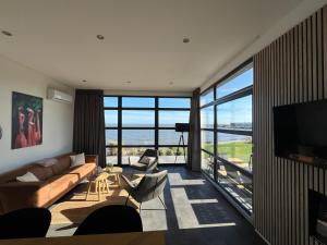 ein Wohnzimmer mit einem Sofa und Stühlen sowie einem großen Fenster in der Unterkunft Traum Chalet am Ijsselmeer in Enkhuizen