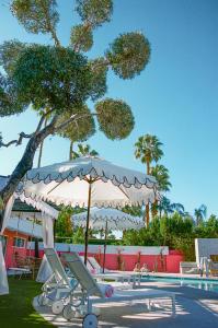 a pool with a white umbrella and a table at The Muse Boutique - Hotel Buyout in Palm Springs