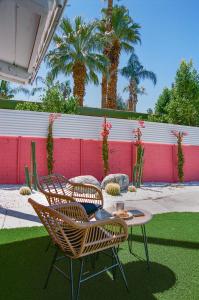 a patio with a table and chairs and palm trees at The Muse Boutique - Hotel Buyout in Palm Springs