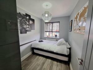 1 dormitorio con cama, ventana y lámpara de araña en Longhorn House - Unique & Luxury Home With Hot Tub, en Horsham St Faith