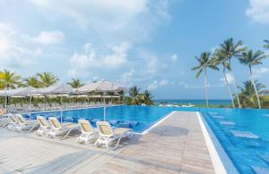a pool at the resort with chairs and the ocean at Riu Sri Lanka All Inclusive in Bentota