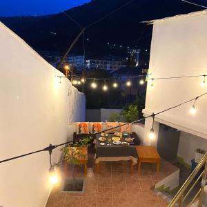 a balcony with a table and chairs and lights at Ziu Guest House in Berat