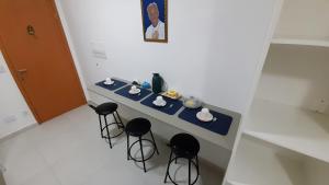 een tafel met drie krukken en een tafel met kopjes bij Apartamento com Garagem no Condomínio da Fé, Pertinho da Canção Nova, Cachoeira Paulista SP in Cachoeira Paulista
