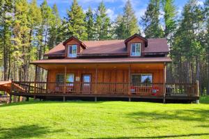 duży drewniany dom z dużym tarasem w obiekcie Blacktail Cabin Hideaway with hot tub w mieście Lakeside
