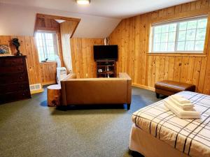 a bedroom with a bed and a couch and a television at Blacktail Cabin Hideaway with hot tub in Lakeside