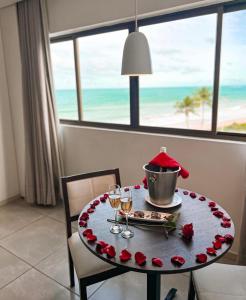une table avec des roses dessus avec vue sur l'océan dans l'établissement Lindo Apto beira-mar no Condomínio do Hotel Ritz Suítes Home Service, à Maceió