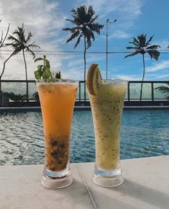 deux cocktails assis sur une table à côté d'une piscine dans l'établissement Lindo Apto beira-mar no Condomínio do Hotel Ritz Suítes Home Service, à Maceió