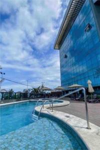 une grande piscine devant un immeuble dans l'établissement Lindo Apto beira-mar no Condomínio do Hotel Ritz Suítes Home Service, à Maceió