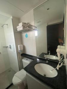 une salle de bain avec un lavabo, des toilettes et un miroir dans l'établissement Lindo Apto beira-mar no Condomínio do Hotel Ritz Suítes Home Service, à Maceió
