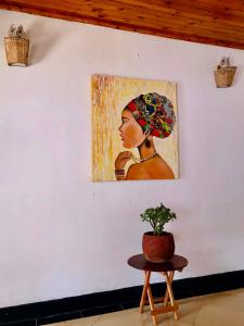 een schilderij van een vrouw aan een muur met een tafel bij COZY NYUMBA in Arusha
