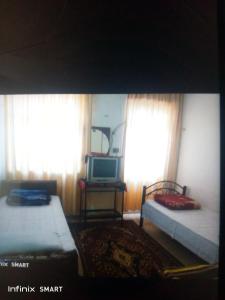 Habitación con 2 camas, TV y ventanas. en Al Amawi Hostel, en Amán