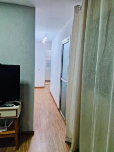 een woonkamer met een televisie en een glazen schuifdeur bij Aconchegante in Campo Grande