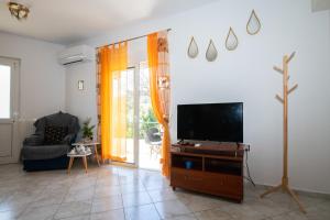 een woonkamer met een televisie en een stoel bij Rodini Sun Apartment in Rhodos-stad