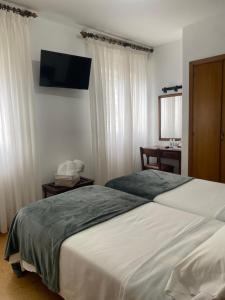 a bedroom with two beds and a television on the wall at Hotel Carabela La Pinta in Baiona