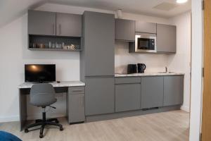 a kitchen with gray cabinets and a desk with a chair at Modern Studio: Old Trafford in Manchester