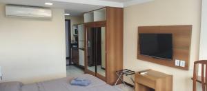 a living room with a bed and a flat screen tv at Nallah ApartHotel in Natal