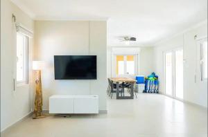 a white living room with a flat screen tv on a wall at Island Oasis Villa in Noord
