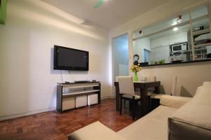 a living room with a television and a table with chairs at Santana Temporada - Bolivar Apartments in Rio de Janeiro