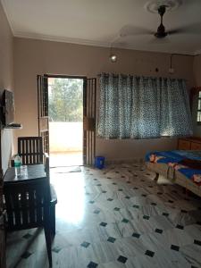 a bedroom with a bed and a desk and a window at Devka villa in Daman