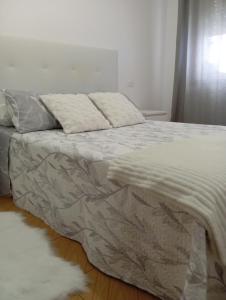 a bed with a blanket and a white rug on the floor at Piso Sol y Mar vacacional in Moaña