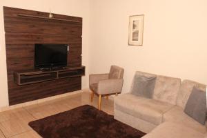 a living room with a couch and a flat screen tv at Casa de Temporada RA Olímpia in Olímpia
