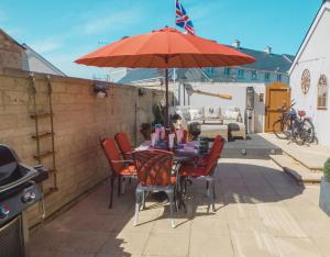 a table and chairs with an umbrella on a patio at PennWay House - Two Bedroom House on Portland Bill with Sea Views! in Southwell