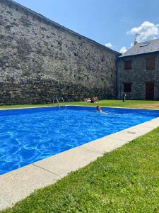 a person in a swimming pool next to a building at Cal Fontcitrana, casa de montaña in Llivia