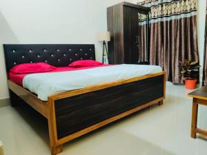 - une chambre avec un grand lit et des oreillers rouges dans l'établissement RAMALAY HOMESTAY, à Ayodhya