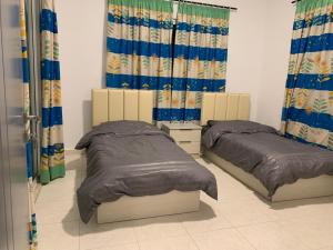 two beds in a room with blue curtains at Jimi Chalet in Al Kafrayn