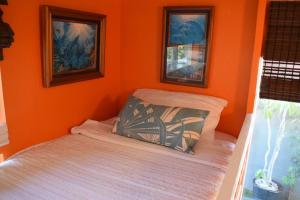 a bedroom with an orange wall with a bed at 7BD 3BA Parking! 2 min drive to Waikiki Beach! in Honolulu