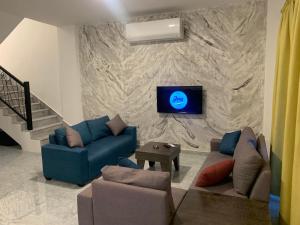 a living room with a couch and a tv on a stone wall at Jimi Chalet in Al Kafrayn