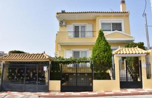 a yellow house with a black gate at Keratea Luxury Villa -Athens Airport in Keratea