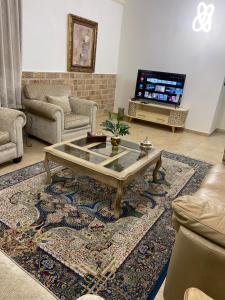 a living room with a coffee table and a tv at Beautiful & Cozy Newly remodeled 2 Bedroom in Amman