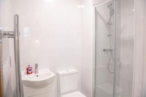 y baño blanco con lavabo y ducha. en Modern Spacious Central Studio en Mánchester