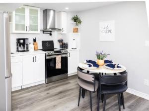 a kitchen with white cabinets and a table with chairs at French Charm in Brampton 2 Bdrm Apt in Brampton
