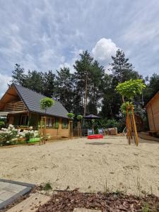 ein Haus mit einem Spielplatz davor in der Unterkunft Domki letniskowe Balia sauna Leśny Czar in Raków