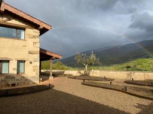 einen Regenbogen am Himmel über einem Haus mit Garten in der Unterkunft Casa Rural La Garza y la Paloma in Navaconcejo