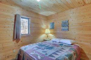 ein Schlafzimmer mit einem Bett in einer Holzhütte in der Unterkunft Dog-Friendly Park Rapids Retreat with Boat Dock! in Arago