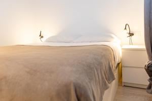 AndBnB I Cerca de Grandvalira con Terraza + Parking gratis في سولديو: سرير في غرفة مع مصباحين على طاولة