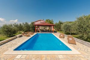 a swimming pool with chairs and a gazebo at Villa Vale in Labin