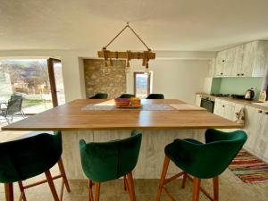 a kitchen with a large wooden table with green chairs at The Old School in Prilep
