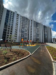 um grande edifício de apartamentos com um parque infantil em frente em 1-комнатная возле Посольства США и Мечети Хазрет Султан em Astana
