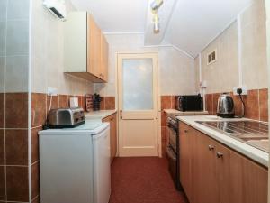 una pequeña cocina con nevera y fregadero en First Floor Apartment en Porthmadog