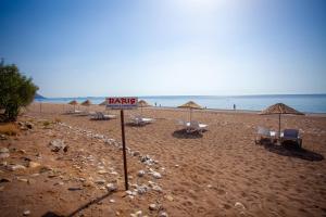 una playa de arena con sillas y sombrillas y el océano en Baris Pension & Bungalows, en Cıralı